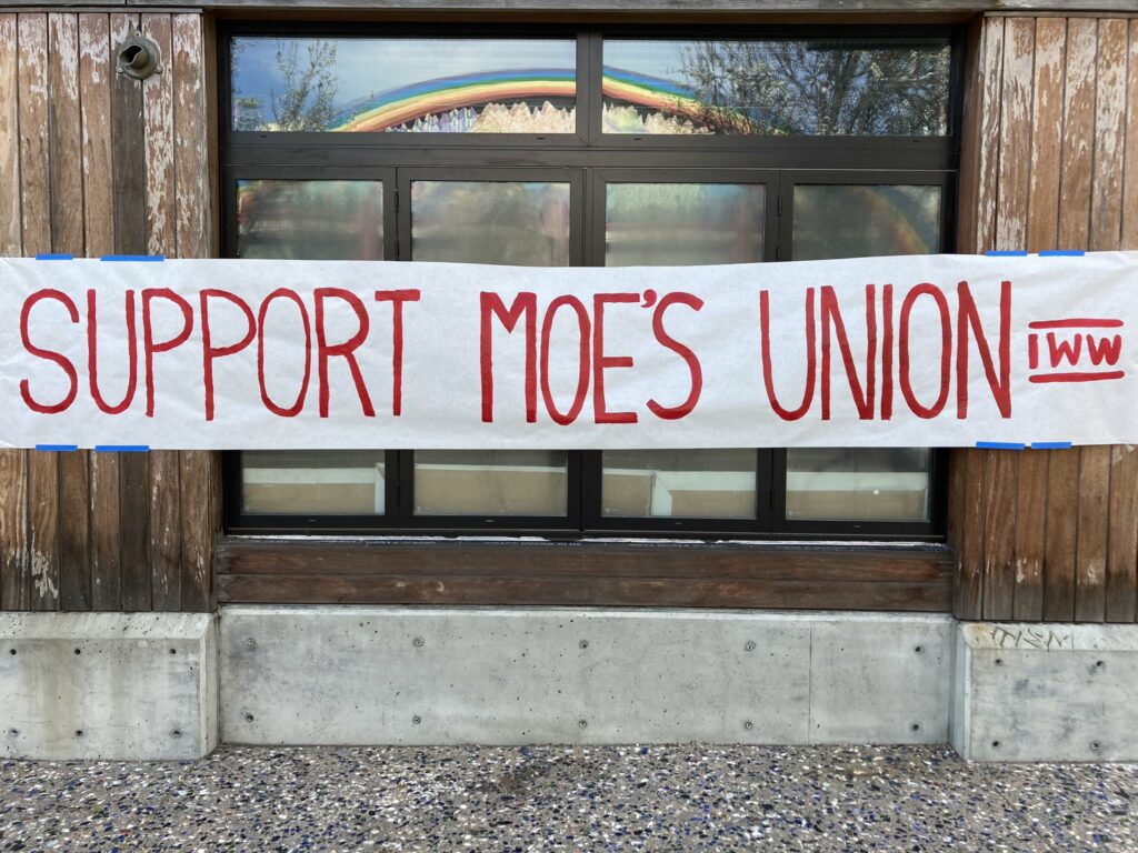Photo shows image of banner with handwritten text that reads "Support Moe's Union" and "IWW"