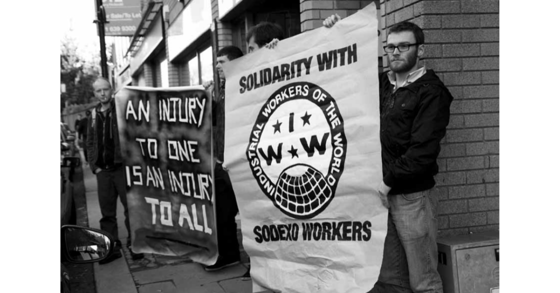 Photo of workers holding picket signs that say "Solidarity with Sodexo Workers"
