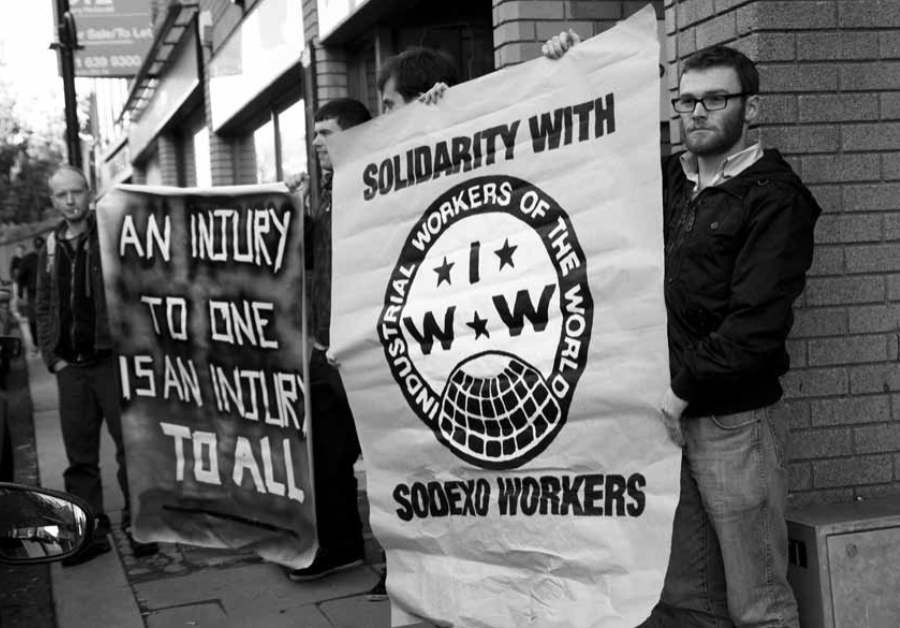 Photo of workers holding picket signs that say "Solidarity with Sodexo Workers"